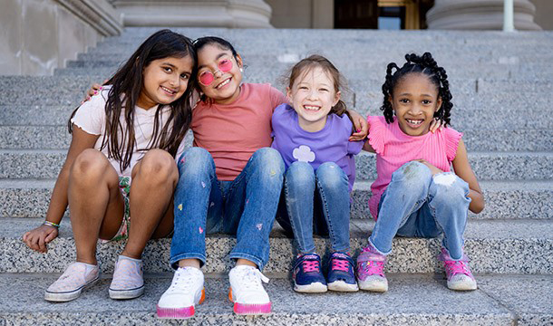 Text on left saying Where Confidence Grows, picture of four girls on steps